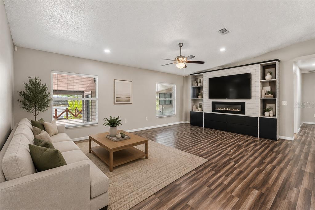 A living room features a light-colored sofa, a wooden coffee table, and a built-in media wall — 1965 ALAMEDA DRIVE, DELTONA, FL
