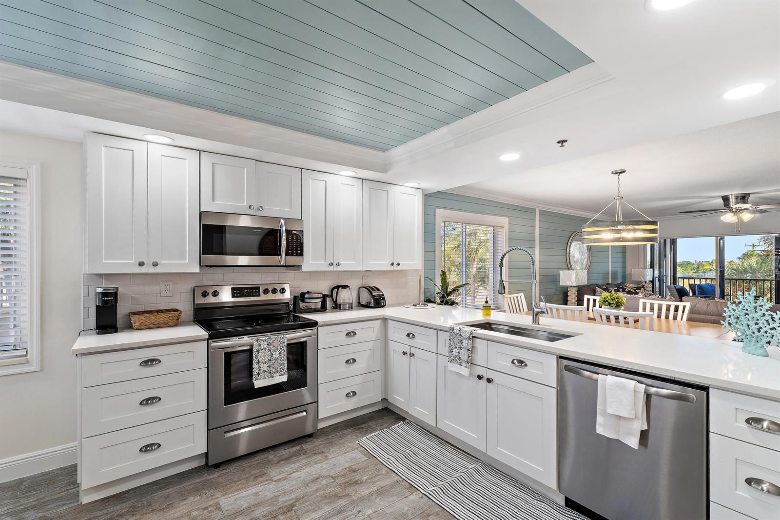 A kitchen with white cabinets, stainless steel appliances, and a light blue shiplap ceiling — 275 Palm Avenue # A301, Jupiter FL 33477, JUPITER, FL