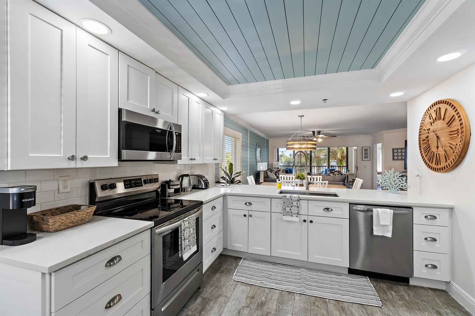 A bright kitchen features white cabinets, stainless steel appliances, and a light blue planked ceiling — 275 Palm Avenue # A301, Jupiter FL 33477, JUPITER, FL