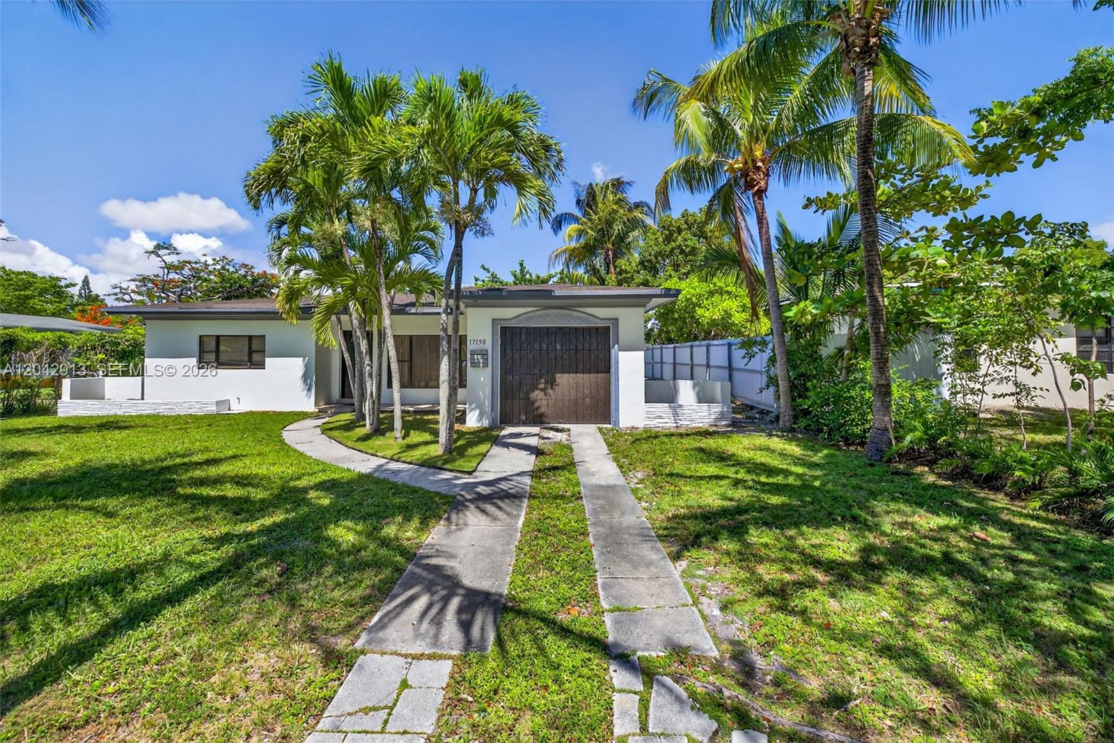 A single-story house with a brown garage door, palm trees, and a concrete driveway — NORTH MIAMI BEACH, FL