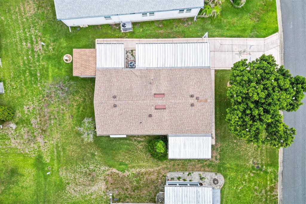 An aerial view shows a house with a shingled roof, a driveway, and a large tree — 1534 HILLCREST DRIVE, LADY LAKE, FL