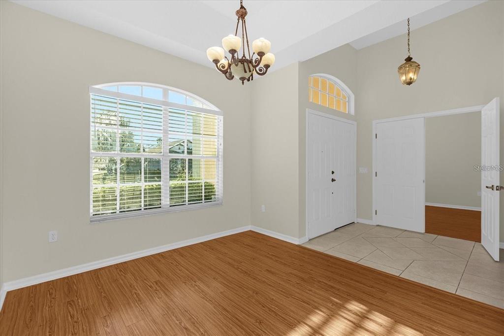 A dining room with wood-look flooring, a chandelier, and an arched window near an entryway — 13131 LUXBURY LOOP, ORLANDO, FL