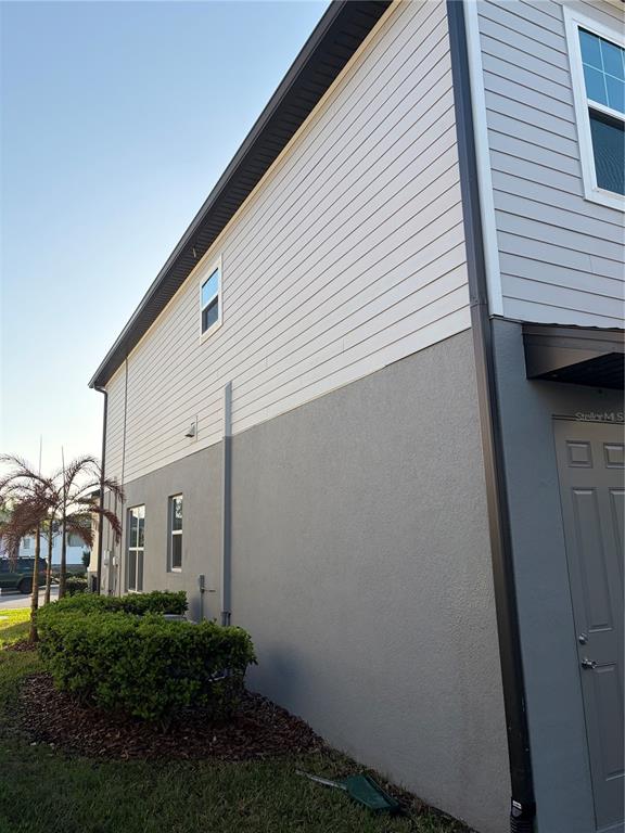 A two-story house with a front porch, gray siding, and a paved driveway — 2910 MELETO BOULEVARD, NEW SMYRNA BEACH, FL