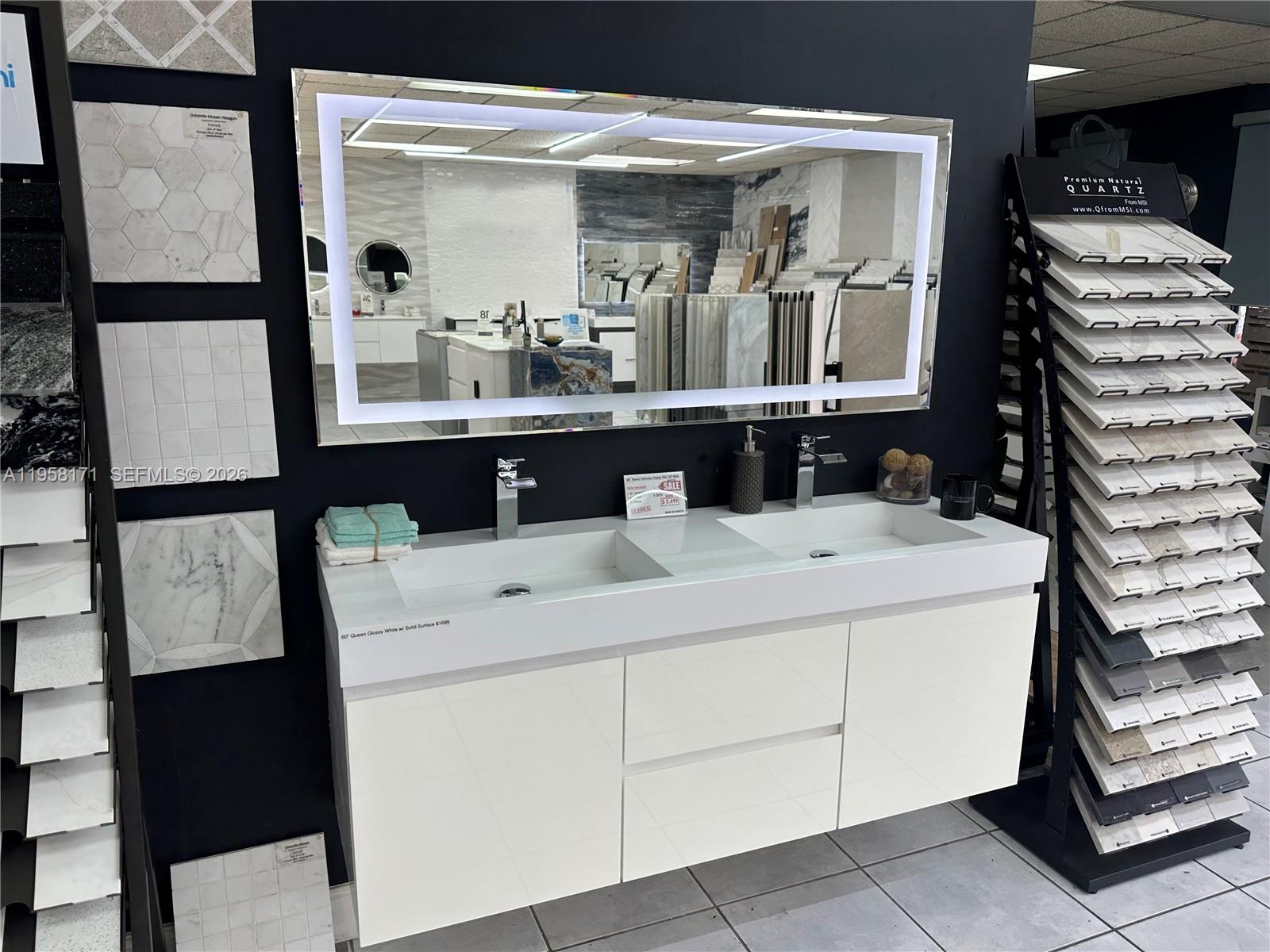 A modern double-sink vanity with a lighted mirror is displayed in a tile showroom — DORAL, Doral FL 33166, DORAL, FL