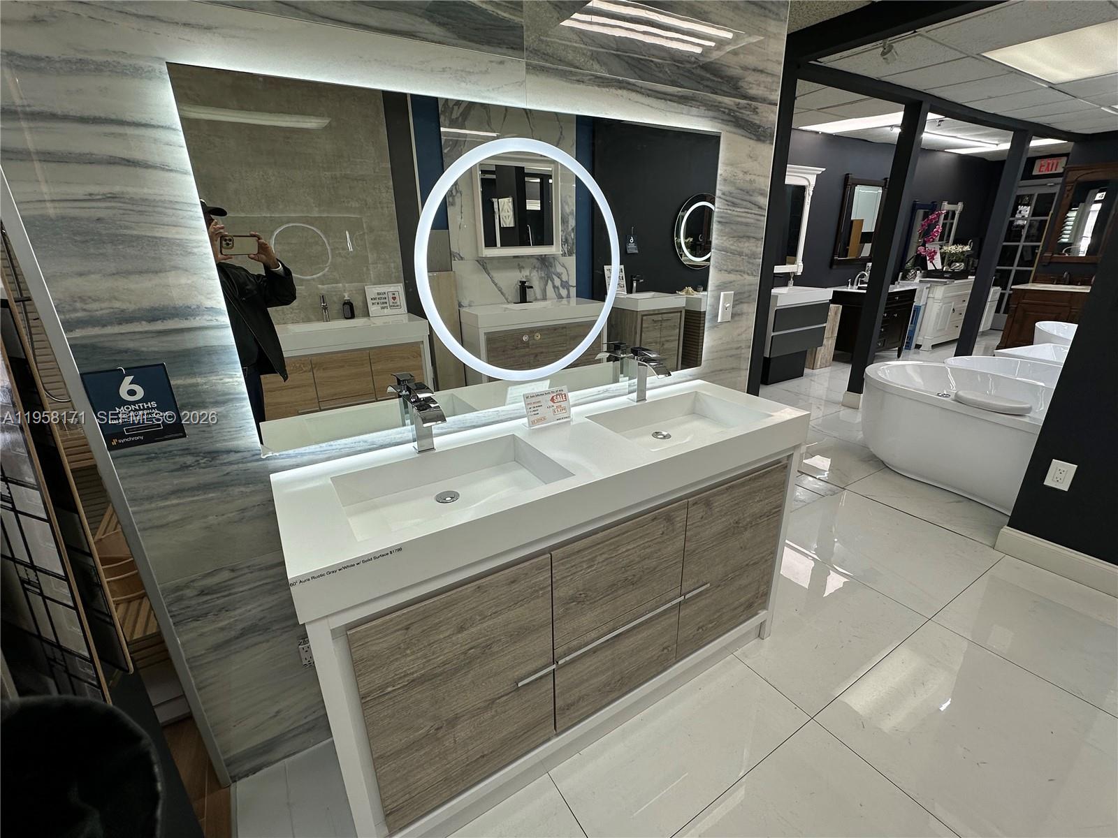 A modern double-sink bathroom vanity with wood-grain cabinets and a large circular LED mirror — DORAL, Doral FL 33166, DORAL, FL