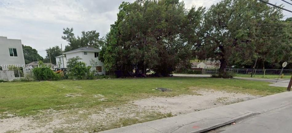 A vacant, grassy lot sits next to a white two-story house and large trees — 2994 NW 46th St, Miami FL 33142, MIAMI, FL