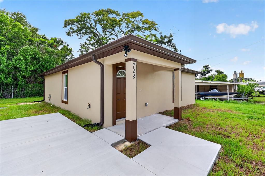 A tan single-story house with a brown front door, covered porch, and concrete walkway — 728 HENRY ST, AUBURNDALE, FL