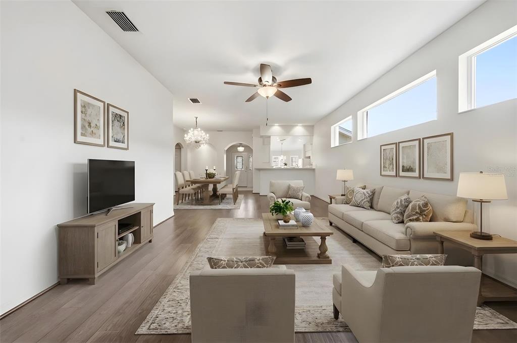 A bright, open-concept living and dining area features light wood floors and neutral furnishings — 27144 STONEY BROOK DRIVE, LEESBURG, FL