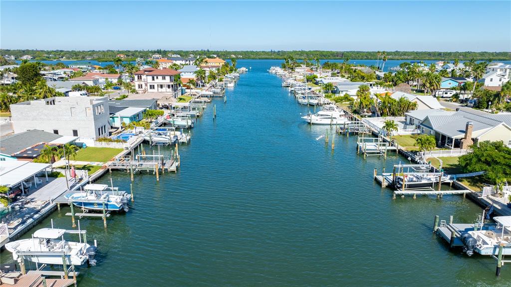 An aerial view shows a canal lined with houses, private docks, and various boats — 17611 1ST STREET E, REDINGTON SHORES, FL