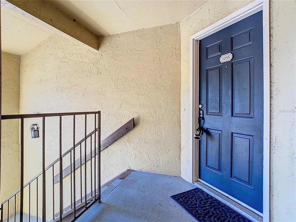 A blue front door with a lockbox and house number 1035 sits on an outdoor landing — 5144 CONROY ROAD UNIT 35, ORLANDO, FL