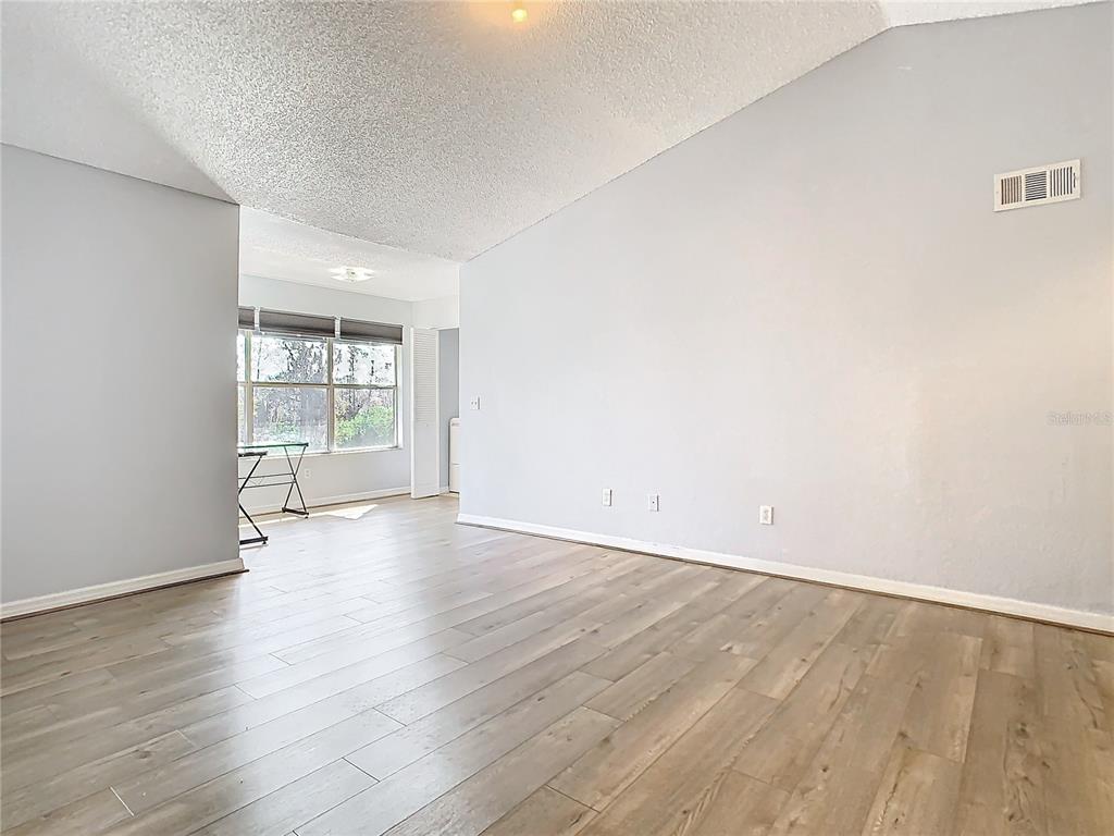 An empty room with light gray walls, wood-look flooring, and a vaulted ceiling — 5144 CONROY ROAD UNIT 35, ORLANDO, FL