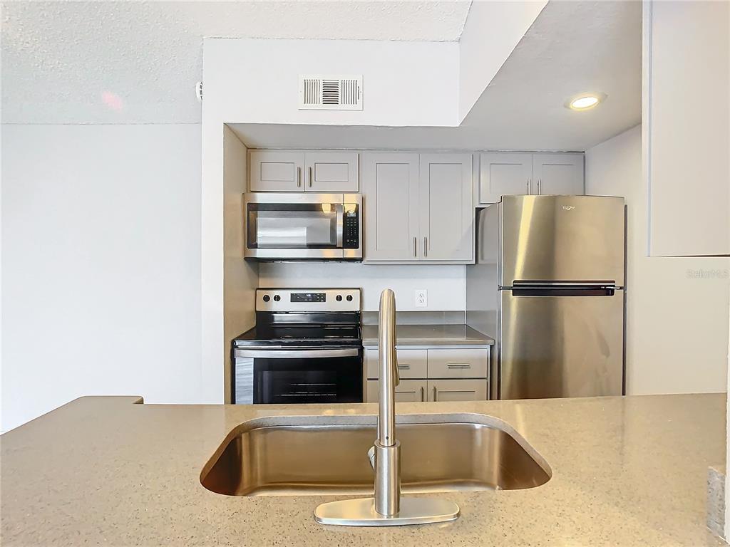 A kitchen features gray cabinets, stainless steel appliances, and a sink set in a countertop — 5144 CONROY ROAD UNIT 35, ORLANDO, FL