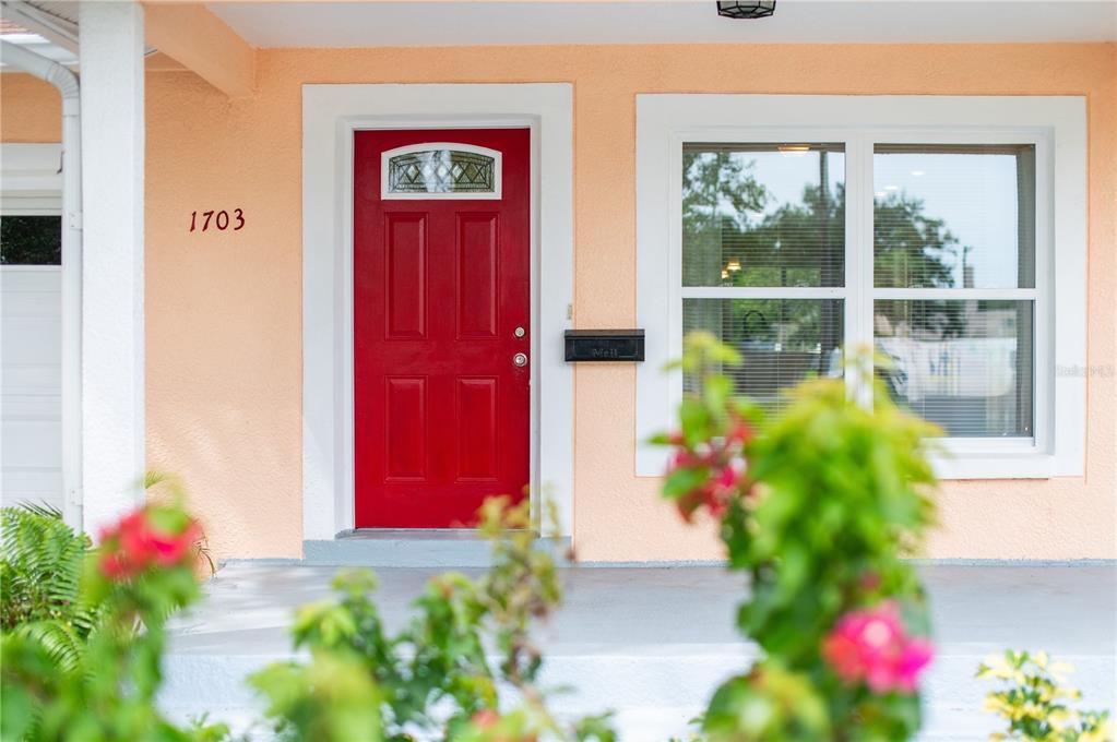 A red front door with a transom window sits on a porch with peach walls — 1703 12TH STREET S, ST PETERSBURG, FL