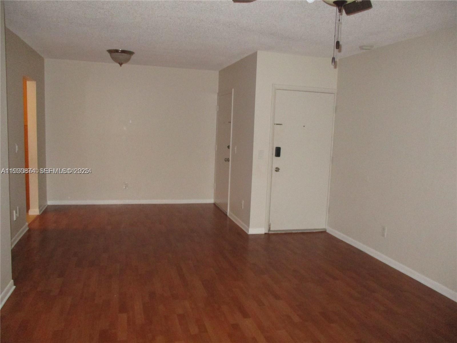 An empty room features light-colored walls, wood-look flooring, and a white entry door — 13726 SW 90th Ave # 26, Miami FL 33176, MIAMI, FL
