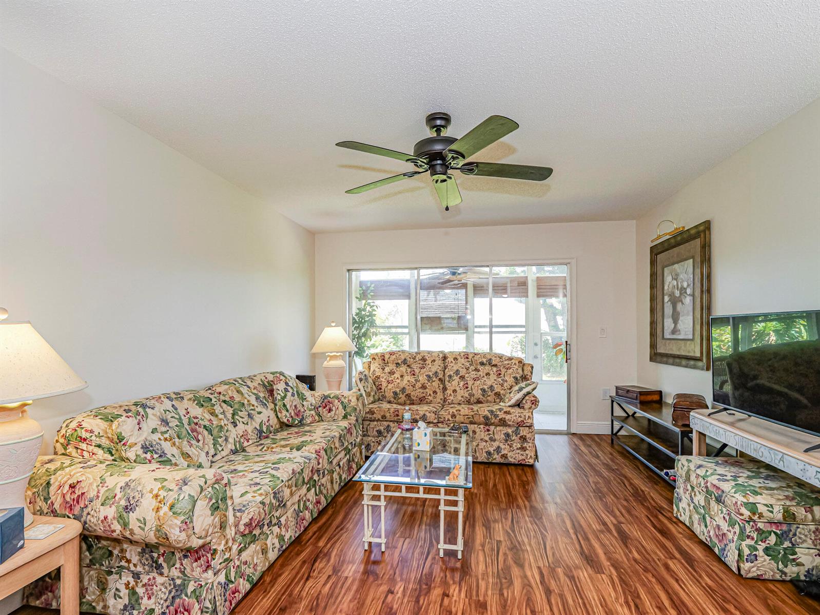 A living room features floral sofas, a glass coffee table, and wood-look flooring — 2800 Indian River Boulevard # 4r, Vero Beach FL 32960, VERO BEACH, FL