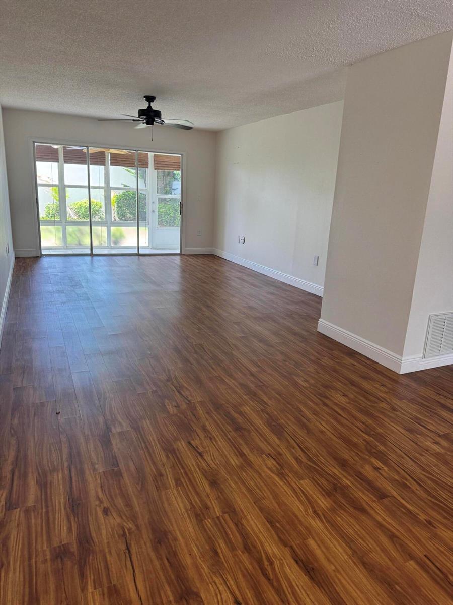 An empty room features wood-look flooring, a ceiling fan, and sliding glass doors to a patio — 2800 Indian River Boulevard # 4r, Vero Beach FL 32960, VERO BEACH, FL