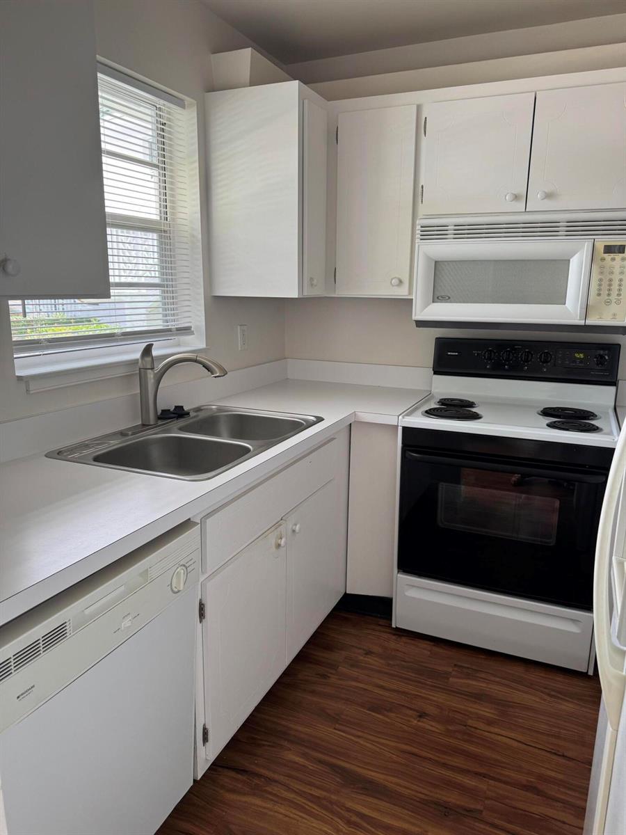 A kitchen features white cabinets, white appliances, a double sink, and wood-look flooring — 2800 Indian River Boulevard # 4r, Vero Beach FL 32960, VERO BEACH, FL