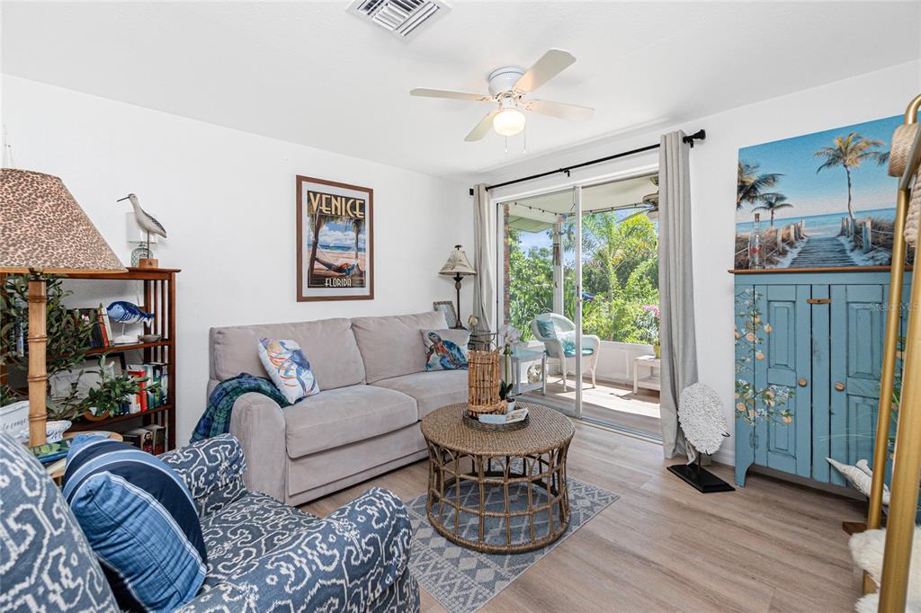 A living room features a beige sofa, patterned armchair, wicker coffee table, and sliding glass doors — 26 FRENCH AVENUE, ENGLEWOOD, FL