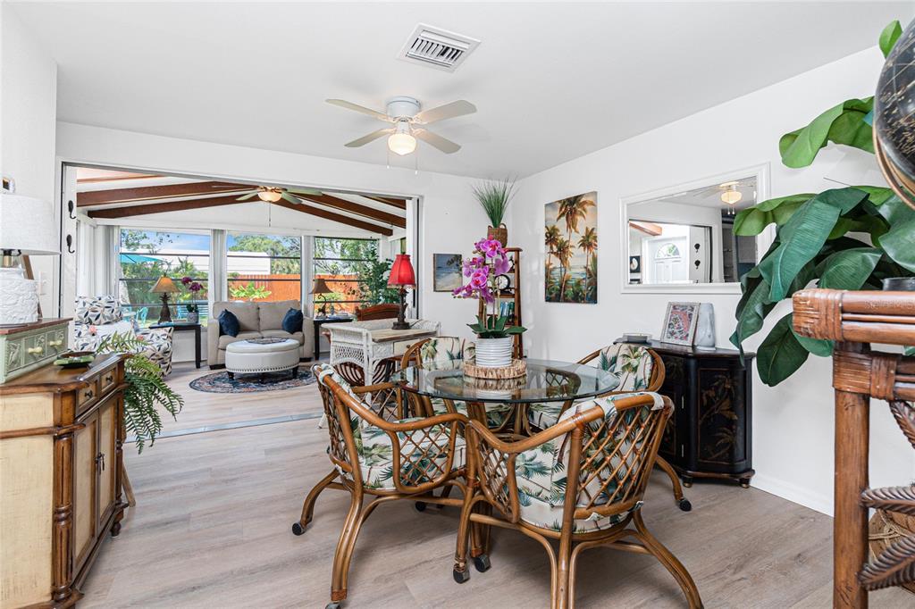A dining area with a glass table and rattan chairs opens into a sunroom — 26 FRENCH AVENUE, ENGLEWOOD, FL