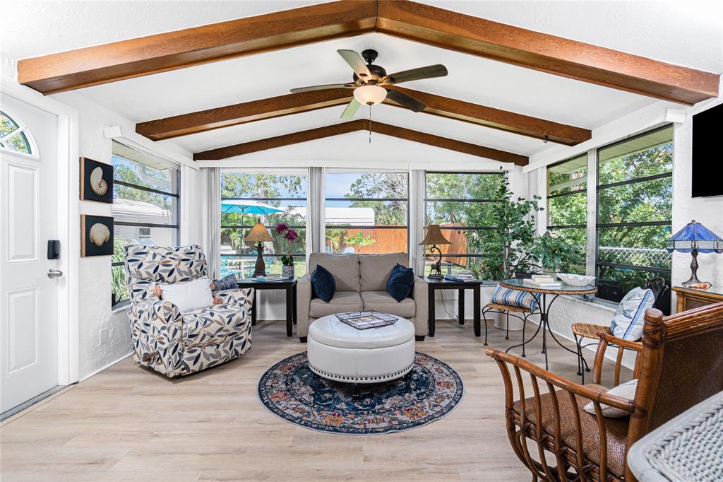 A sunroom features a vaulted ceiling with exposed wood beams, large windows, and casual furniture — 26 FRENCH AVENUE, ENGLEWOOD, FL