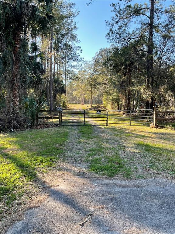 A metal gate blocks a dirt path leading into a wooded area — 10379 NE HIGHWAY 314, SILVER SPRINGS, FL