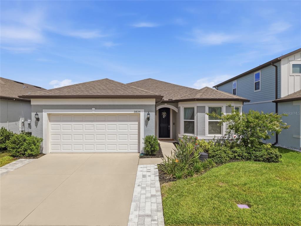 A single-story house with a two-car garage, gray exterior, and a paved walkway — 3834 MAPLE BAY LANE, LAND O LAKES, FL