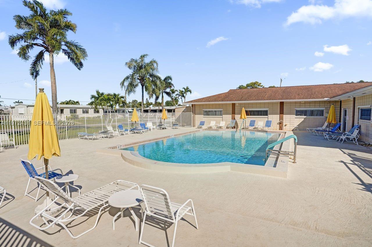 An outdoor swimming pool is surrounded by lounge chairs, umbrellas, and palm trees — 4035 Marigold Rd, Boynton Beach FL 33436, BOYNTON BEACH, FL