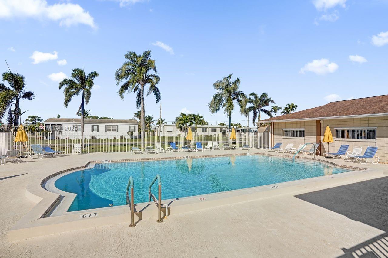 An outdoor swimming pool with lounge chairs and palm trees in a residential area — 4035 Marigold Rd, Boynton Beach FL 33436, BOYNTON BEACH, FL
