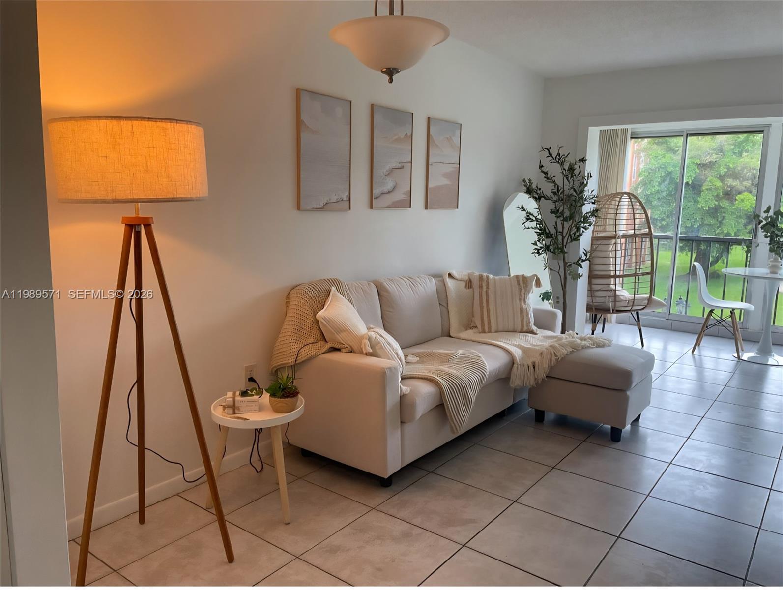 A living room features a beige sofa, a tripod floor lamp, and a balcony view — 9405 W Flagler St # D204, Miami FL 33174, MIAMI, FL