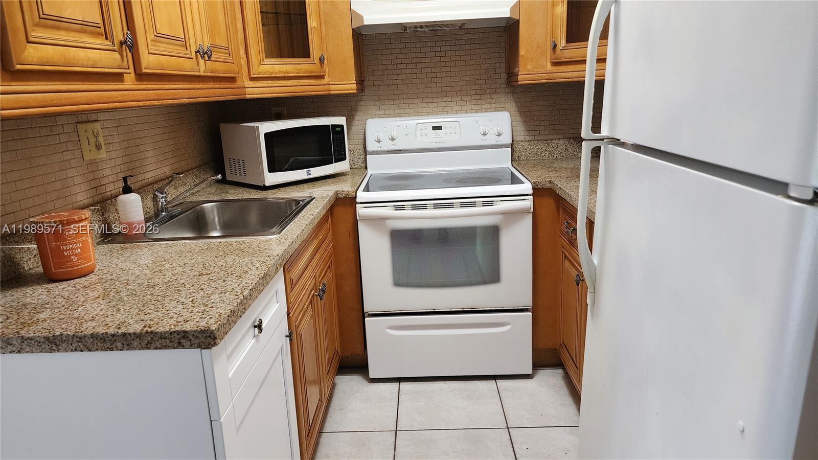 A kitchen features wooden cabinets, granite countertops, a white stove, and a white refrigerator — 9405 W Flagler St # D204, Miami FL 33174, MIAMI, FL