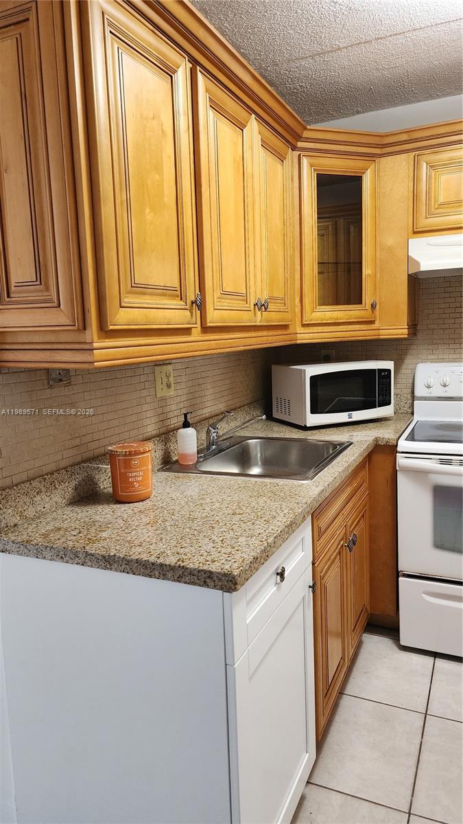 A kitchen features light wood cabinets, granite countertops, a stainless steel sink, and white appliances — 9405 W Flagler St # D204, Miami FL 33174, MIAMI, FL