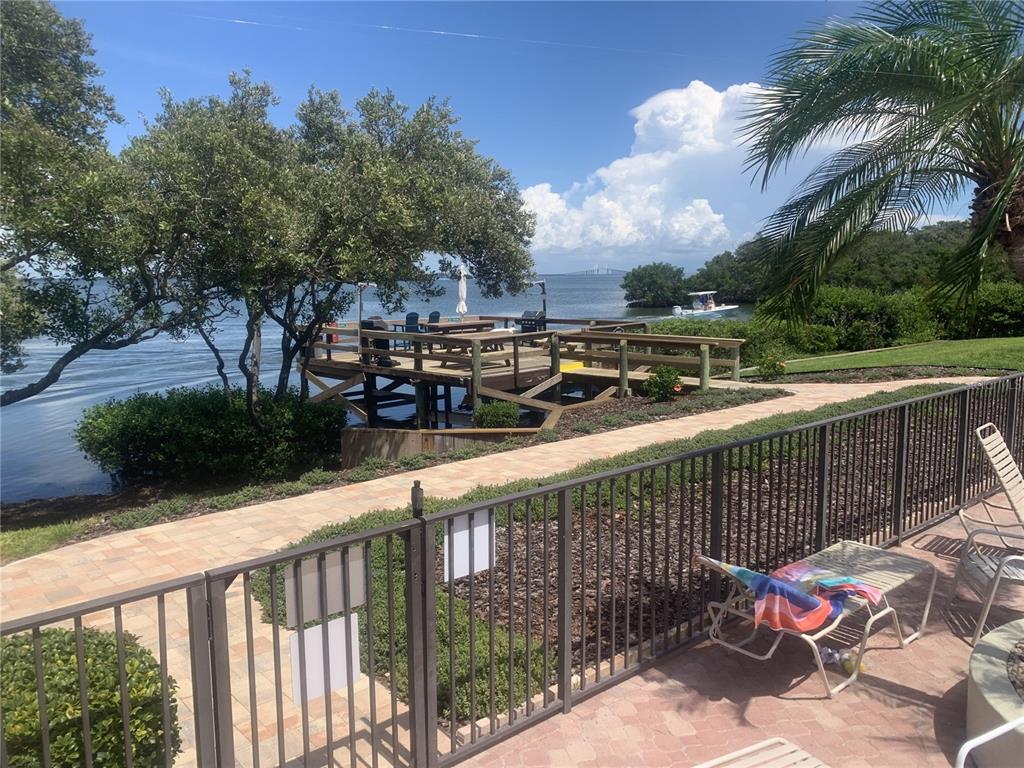 A wooden deck overlooks the water with a paved walkway and a metal fence nearby — 1515 PINELLAS BAYWAY S UNIT 34, ST PETERSBURG, FL