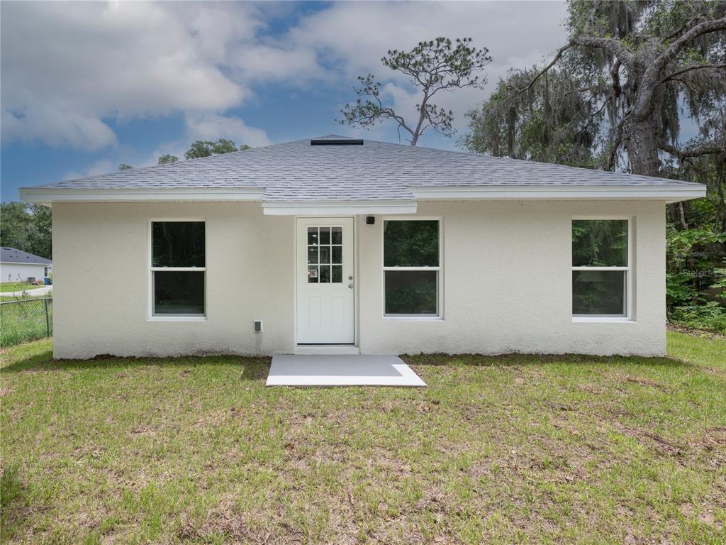A single-story house with a white stucco exterior, a gray shingled roof, and a front door — 520 W BERESFORD AVENUE, DELAND, FL
