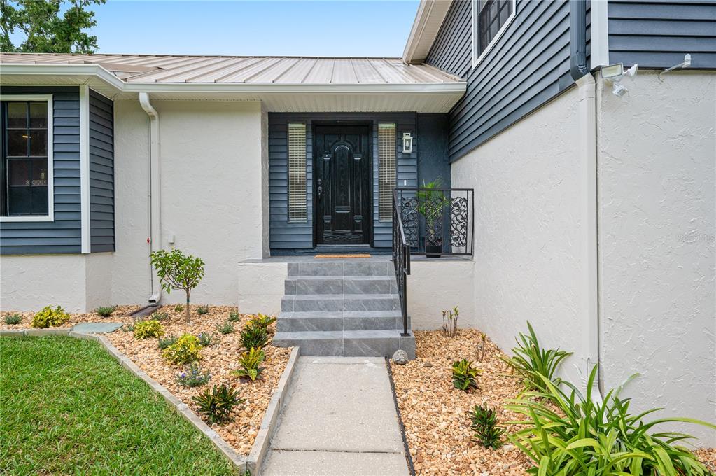 A two-story house with a metal roof, blue siding, and a white stucco lower level — 3829 ERIC COURT, LAKELAND, FL