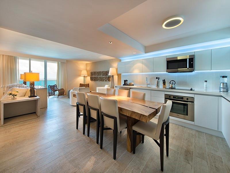 A modern open-concept kitchen and dining area features a live-edge wood table and white cabinetry — 102 24th St # 1540, Miami Beach FL 33139, MIAMI BEACH, FL
