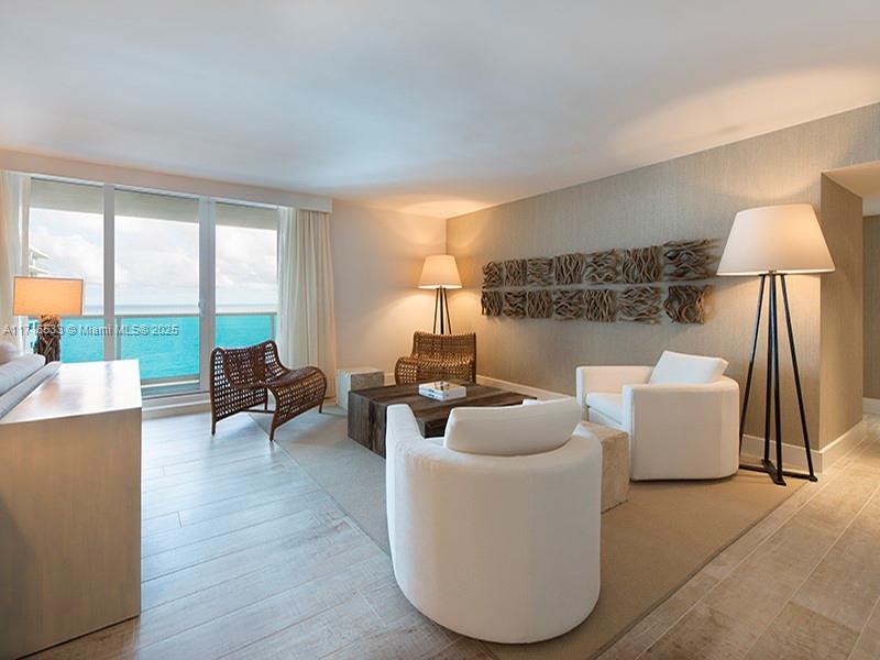 A living room with white armchairs, a wooden coffee table, and an ocean view — 102 24th St # 1540, Miami Beach FL 33139, MIAMI BEACH, FL