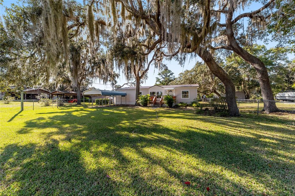 A kitchen with white cabinets, light countertops, wood-look flooring, and an adjacent laundry area — 2008 N RETREAT, INVERNESS, FL