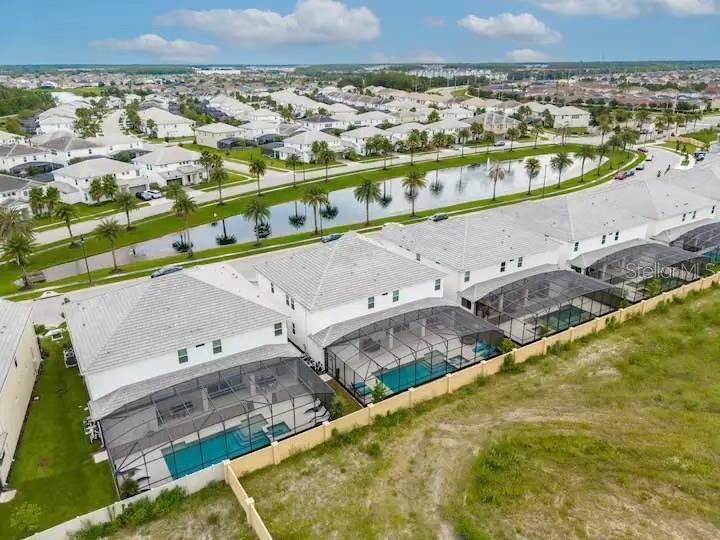 An aerial view shows several houses with screened-in pools backing onto a pond — 3870 SONOMA BLVD, KISSIMMEE, FL