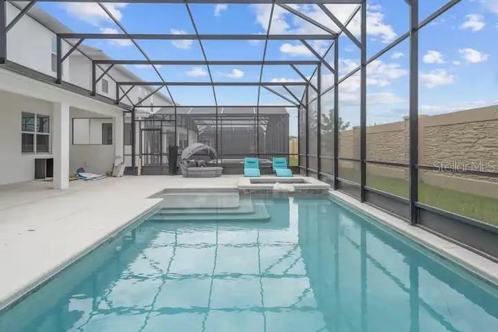 A screened-in swimming pool and hot tub sit on a patio beside a two-story house — 3870 SONOMA BLVD, KISSIMMEE, FL