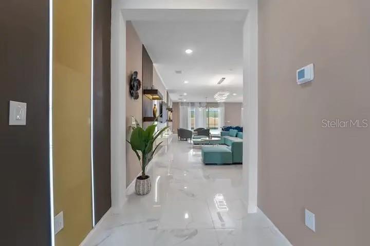 A view from a hallway looking into a living room with white marble-style flooring — 3870 SONOMA BLVD, KISSIMMEE, FL