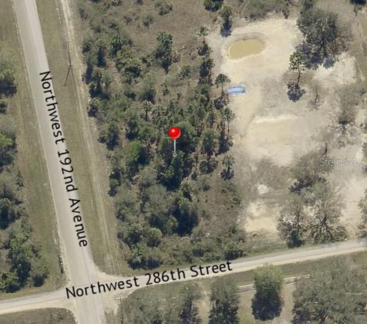 This aerial view shows a wooded, undeveloped corner lot at a road intersection — 19218 NW 286TH STREET, OKEECHOBEE, FL