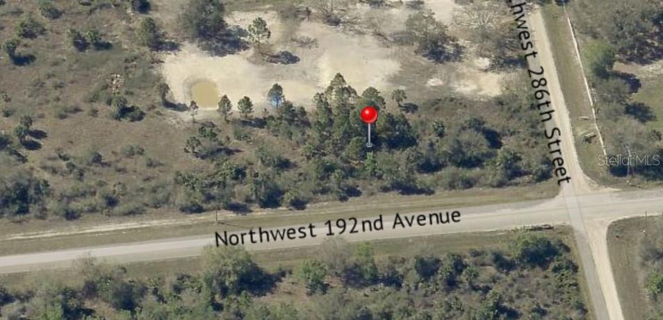 This aerial view shows a vacant, wooded lot located at a street intersection — 19218 NW 286TH STREET, OKEECHOBEE, FL