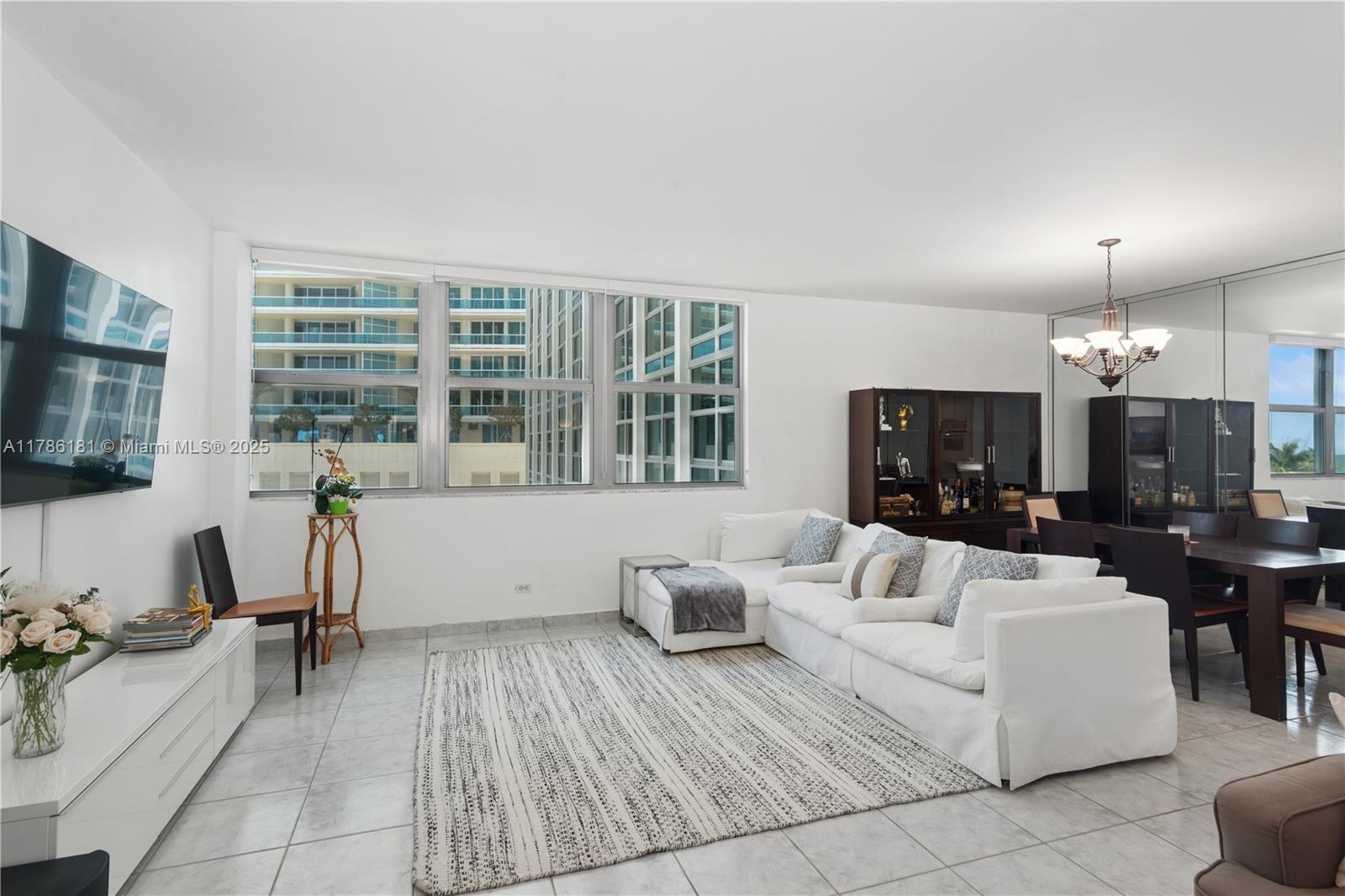 A bright living and dining area features white tile floors, a sectional sofa, and windows — 5055 Collins Ave # 5F, Miami Beach FL 33140, MIAMI BEACH, FL