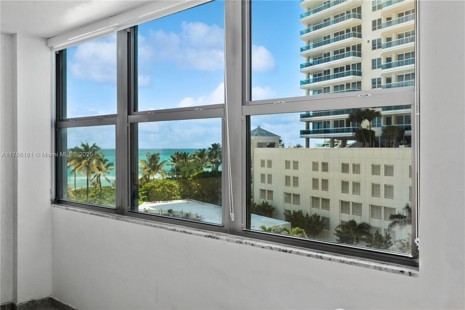 A view of the ocean and nearby buildings through a large, multi-pane window — 5055 Collins Ave # 5F, Miami Beach FL 33140, MIAMI BEACH, FL
