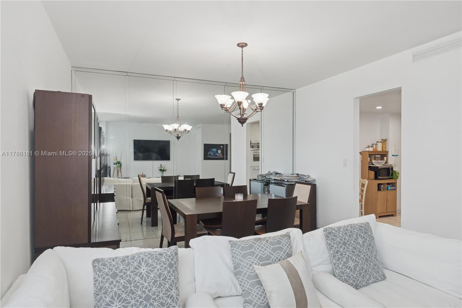 A dining area features a dark wood table, chairs, and a large mirrored wall — 5055 Collins Ave # 5F, Miami Beach FL 33140, MIAMI BEACH, FL