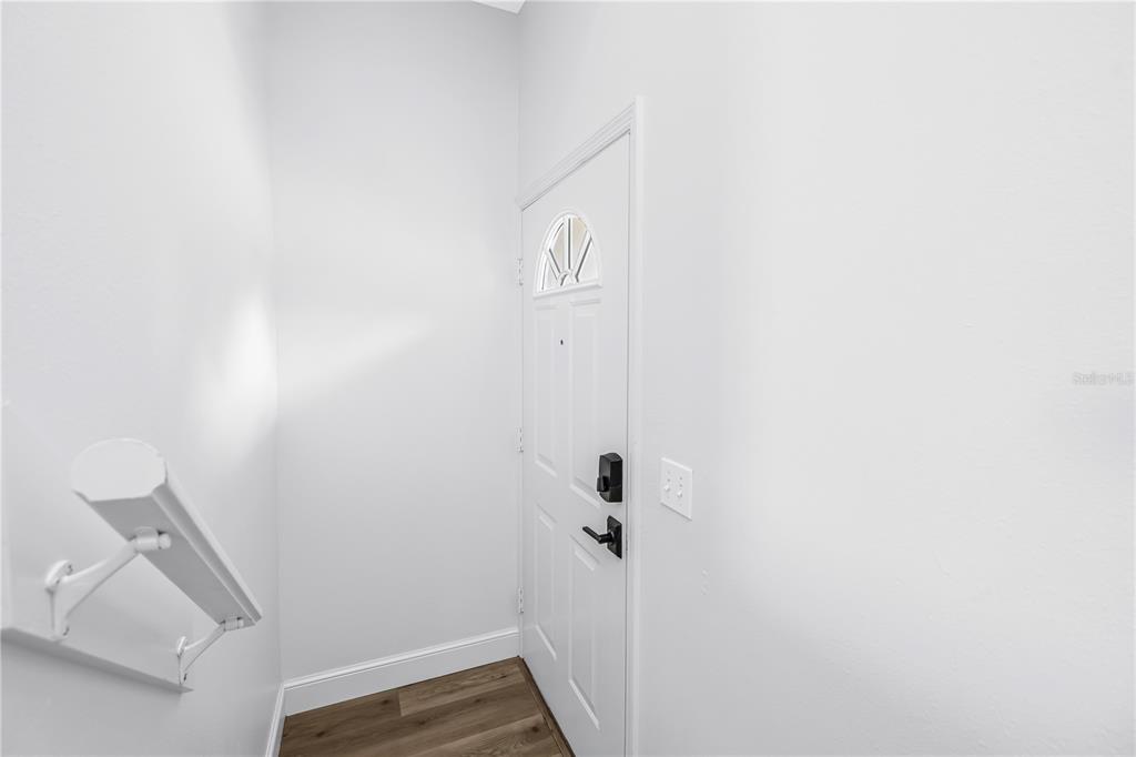 A white front door with a small window sits in a room with wood flooring — 8350 WINGATE DRIVE UNIT 925, SARASOTA, FL