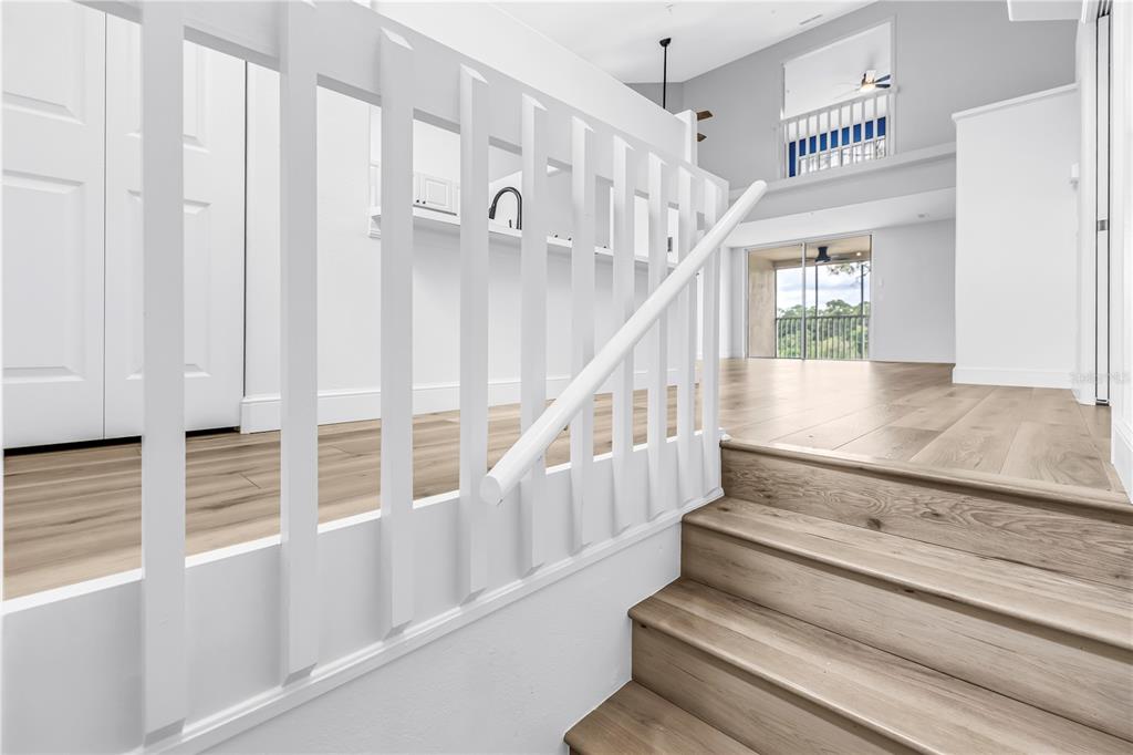 A staircase with white railings leads to an open living area with light wood flooring — 8350 WINGATE DRIVE UNIT 925, SARASOTA, FL
