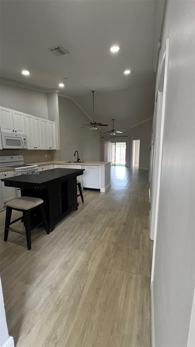 A kitchen with white cabinets, a black island, and light wood-look flooring — 11065 NW 38th Pl, Sunrise FL 33351, SUNRISE, FL