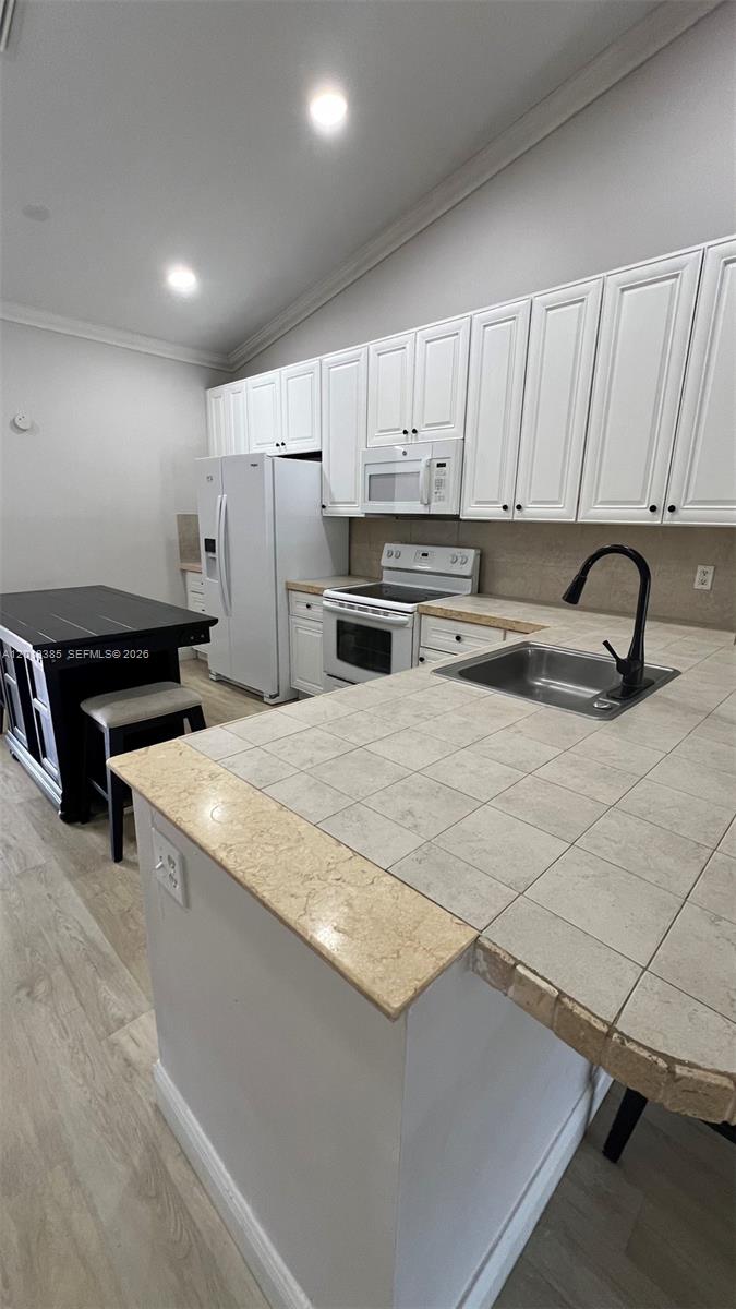 A kitchen features white cabinets, a tiled countertop, a black faucet, and a black island — 11065 NW 38th Pl, Sunrise FL 33351, SUNRISE, FL