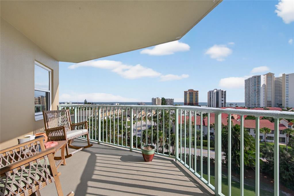 A balcony with two rocking chairs overlooks a coastal city and the ocean — 4 OCEANS WEST BOULEVARD UNIT 705D, DAYTONA BEACH, FL